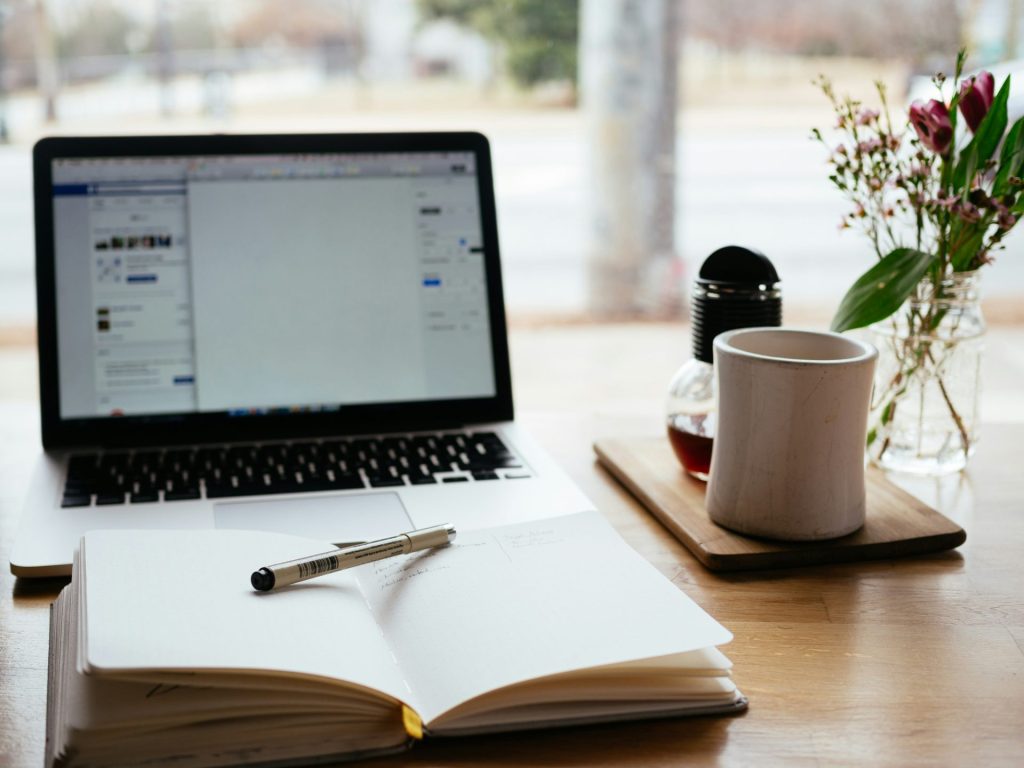 MacBook Pro cerca del libro abierto blanco