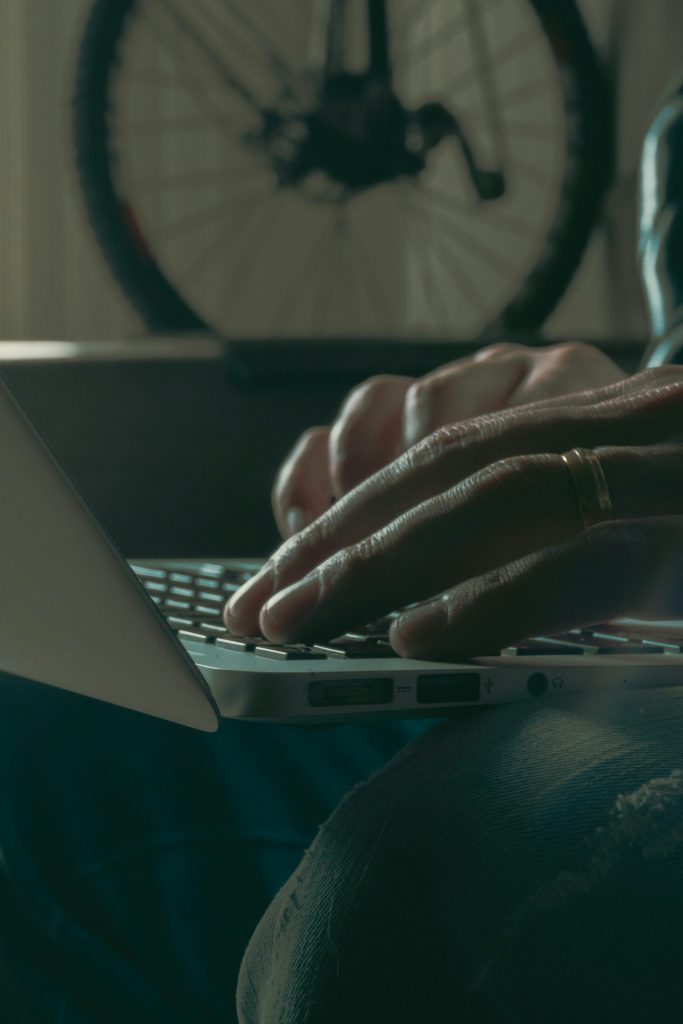 una persona escribiendo en una computadora portátil con una bicicleta al fondo